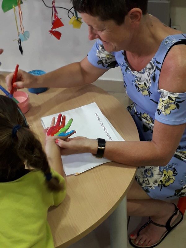 photo of special needs assistant and child with paint in classroom